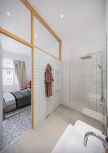 A minimalist bathroom features white grid-patterned tile walls and concrete flooring, creating a clean and modern aesthetic.