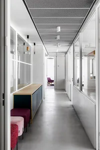 A minimalist office with concrete flooring, glass partitions, and modern furniture.