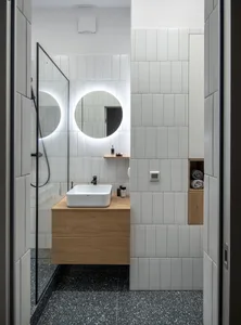 Modern bathroom with white terrazzo tile flooring, white wall tiles, and wooden vanity.