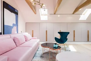 Modern living room featuring a pink leather couch, white and gold coffee tables, and grey cabinets
