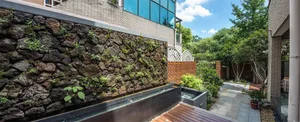 Modern landscape design featuring concrete walls, stone plants, and wooden deck.