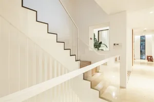 A modern interior staircase with glass railings, stone steps, and wooden accents.