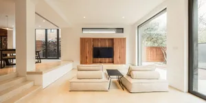 Modern living room with minimalist, neutral-colored seating and large windows