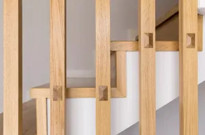 Close-up of minimalist wooden stairs with white steps and wooden railings.