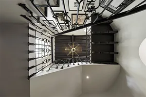 A black metal staircase with intricate railings leading to a white interior space.