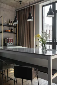 Industrial-style living room with concrete floor, metal furniture, and large windows.