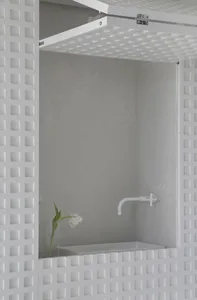Modern bathroom with a sink mounted on a wall, featuring a white concrete panel.