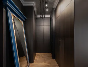 A modern hallway with dark wooden storage cabinets and a leaning mirror.