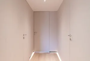 A modern hallway featuring smooth light wood flooring and minimalist design.