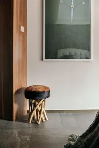 A modern interior design featuring a wooden stool with a leather seat and backrest.