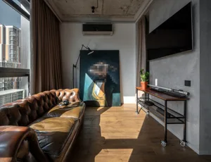 Living room with a modern leather couch, industrial lighting, and wood flooring.