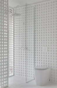 Modern minimalist bathroom featuring white patterns, porcelain fixtures, and a glass-enclosed shower.