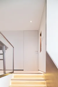 Modern minimalist interior space featuring wooden stairs and glass railings.