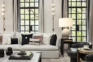 A modern minimalist living room with a white sofa, black and white pillows, and a marble coffee table.