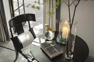 A glass side table with decorative items including a gold sculpture of a panther on a crystal ball, a candle in a glass holde