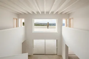 A minimalist concrete residential interior with a view of the sea and mountains.