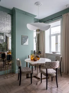 A modern dining room with a round marble table and upholstered chairs featuring a geometric pattern.