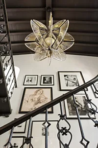 A modern interior featuring a black metal staircase and a chandelier with clear and gold-colored glass.