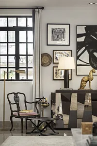 A modern living room featuring metallic accents, a cozy chair with a pink cushion, and framed artwork on the wall.