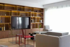 A modern living room featuring a large flat-screen TV, comfortable seating, and stylish decorative items.