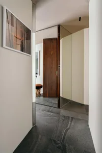 A modern, minimalist entryway with a dark wooden door and concrete flooring.