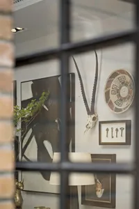 A wall displaying various decorative art pieces, including a mounted skull, a woven basket, and framed keys.