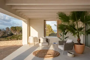 Modern minimalist terrace with concrete flooring, wooden beams, and rattan furniture