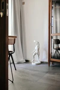 A modern concrete living room with minimalist furniture and a sculptural white statue.
