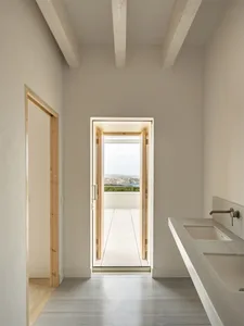 Modern minimalist bathroom with concrete floor and walls, glass door opening to outdoor patio.