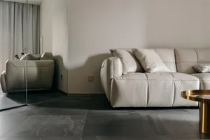 Modern white leather sofa with pillows in a minimalist living room setting.