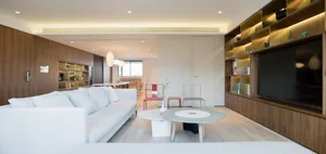 Modern minimalist living room with wood accents, featuring a white sectional sofa, a stylish coffee table, and a large wooden