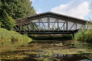 Modern residential architecture featuring a steel and glass bridge crossing a river.