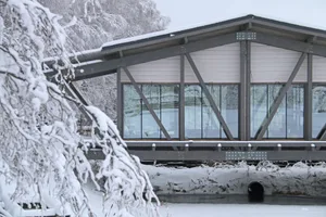 A metallic residential bridge with glass panels over a snowy landscape.