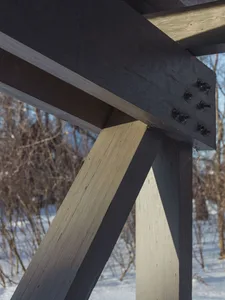 A close-up view of a wooden construction detail with a focus on the joinery and bolts.