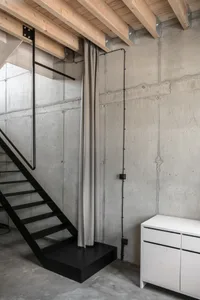 Industrial black metal staircase with concrete walls and ceiling beams