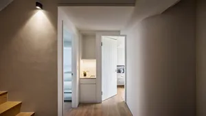 Minimalist apartment interior with wooden flooring and white doors.