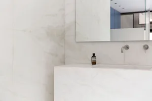 Modern bathroom with marble walls and a white porcelain sink.