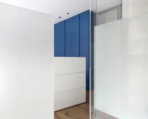 A modern interior design featuring glass doors, white panels, and blue panels in a room with wooden flooring.