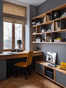 A modern home office with a wooden desk and shelves filled with books and toys.