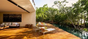 Modern minimalist poolside deck featuring a wooden deck, lounge chairs, and a swimming pool surrounded by lush greenery.