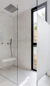 Modern minimalist bathroom with white marble walls and floor.