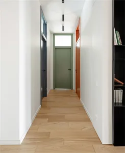 A modern interior corridor with white walls, light wooden flooring, and colorful doors.