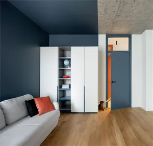 A modern living room with concrete walls, white cabinets, and hardwood floors.