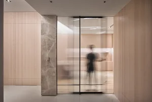 A modern living room featuring glass walls, wooden floors, and contemporary furniture.
