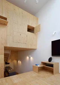 A modern living room featuring wooden paneling with a loft space and integrated furniture and lighting.
