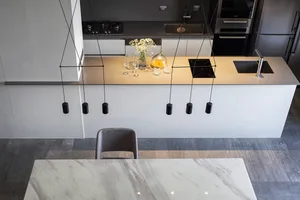 A modern, minimalist kitchen featuring marble countertops and stainless steel appliances.
