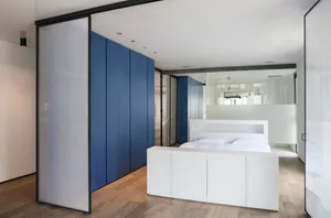 Modern bedroom with white furniture, blue storage cabinets, and glass partition, featuring white floor and wood flooring.