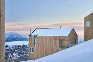 Modern residential house covered in snow with wooden exterior during winter