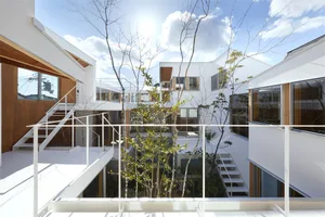 A residential house with a white stucco exterior, featuring a courtyard with trees and modern design elements.
