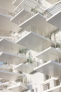 Modern apartment buildings with balconies featuring metal mesh railings.